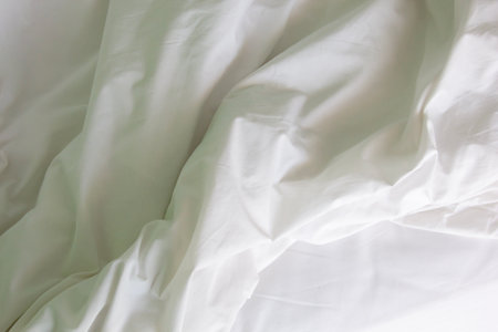 wrinkled white bedding showing texture and folds of duvet and blanketの写真素材