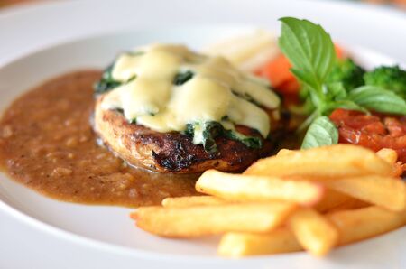 Grilled chicken steak served with chips, potatoes and vegetablesの写真素材