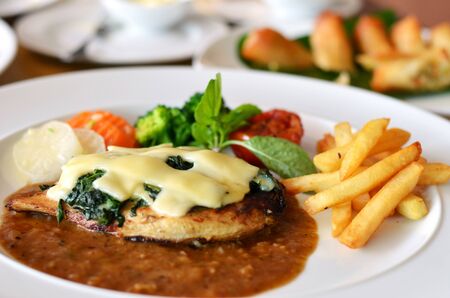 Grilled chicken steak served with chips, potatoes and vegetablesの写真素材