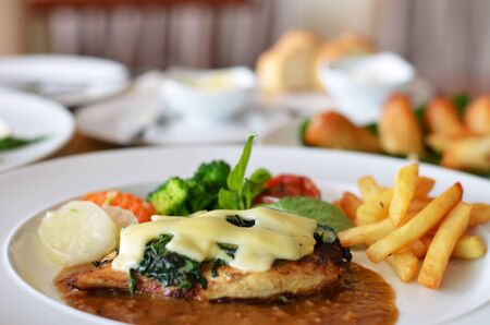 Grilled chicken steak served with chips, potatoes and vegetablesの写真素材