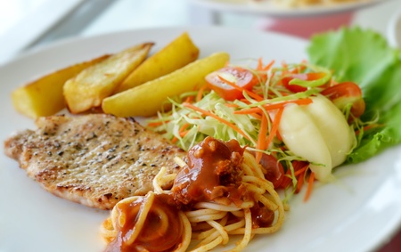 Grilled pork steak served with chips, potatoes and vegetables , macaroniの写真素材