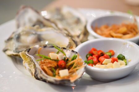 Oysters  with chilli and fried garlic , on white plateの写真素材