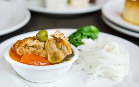 Red curry with roast duck served with vegetable  and rice vermicelli on white plateの写真素材