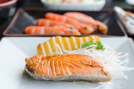 fish steak and fresh vegetable on white plateの写真素材