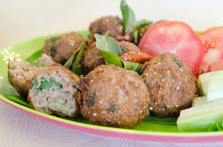 close up meatballs served with fried  bergamot leaves and fresh vegetable on plate