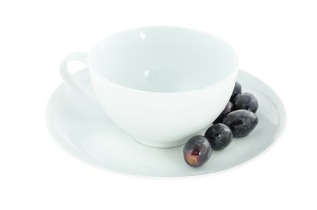 empty white cup and black grapes on plateの写真素材