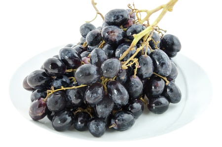 close up black  grapes  fruits on white plate over white backgroundの写真素材