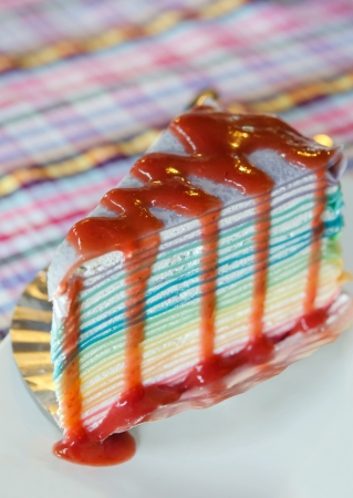 colorful  crepe cake on white plate with strawberry syrupの写真素材