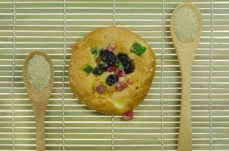 top view of  bread with raisin and  dried fruits and two spoon of sugar on wooden background 