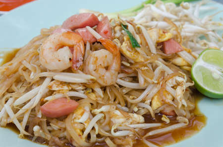 close up stir fried  noodles with shrimp ,sausage ,  egg  and fresh vegetable  served with slice limeの写真素材