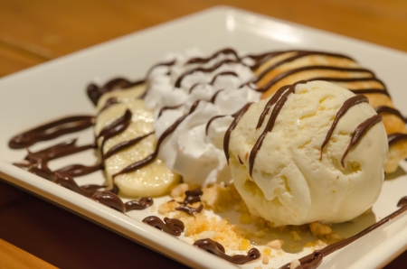 close up vanilla ice cream and crepes with banana , chocolate sauce  served with whipping cream and ripe banana on dishの写真素材