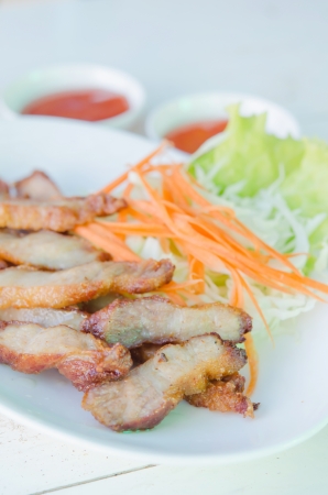 slice grilled pork  served with fresh vegetable and sauce  on dishの写真素材