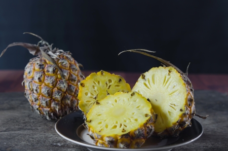 ripe pineapple with slices over wooden boardの写真素材