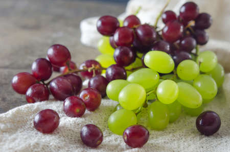 red and green grape in wooden basket over sackclothの写真素材