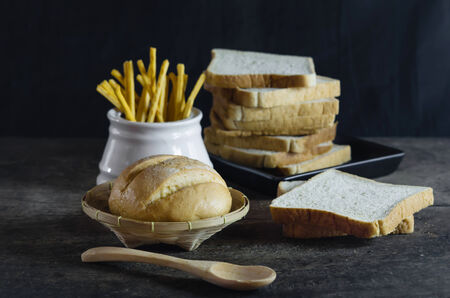 Different types of bread with spoon and basket on  wooden tableの写真素材