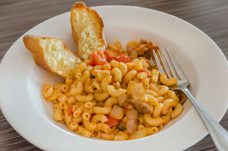 Italian tomato pasta served with garlic breadの写真素材