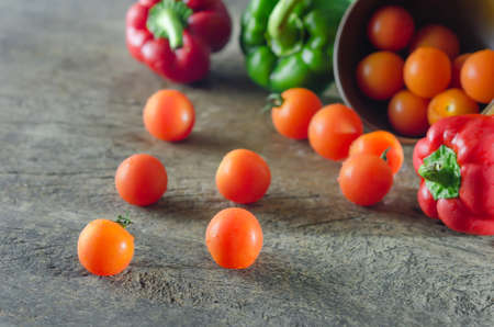 Red cherry tomatoes   and bell pepper on a textured  wooden backgroundの写真素材