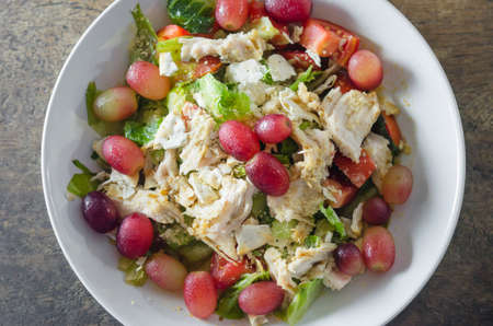 Mix salad with grapes and chicken on white dishの写真素材