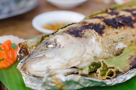 Grilled fish on green banana leaf with herbsの写真素材