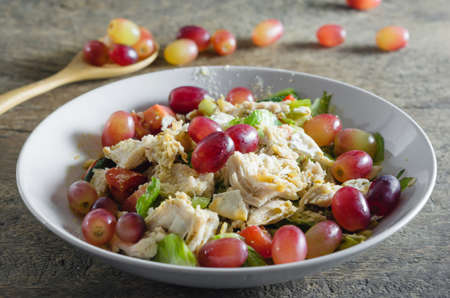 Mix salad with grapes and chicken on white dishの写真素材