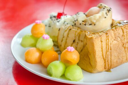 Honey toast topped  with ice cream cantaloupe and melon on dishの写真素材