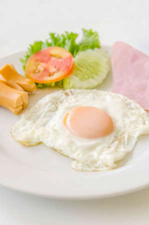 Fried eggs and sausage on a white  plateの写真素材