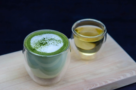 closeup cup of green tea latte on wooden plateの写真素材