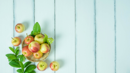 Top view red and yellow apple with leaves and  bamboo basket on  white wooden background with free...