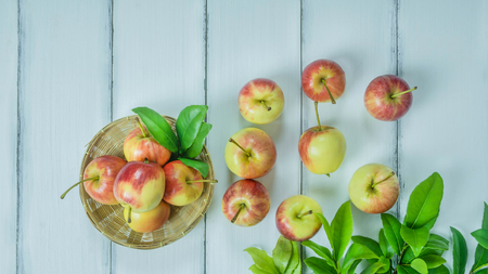 Top view red and yellow apple with leaves and  bamboo basket on  white wooden background with free...