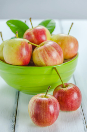 fresh red and yellow apple with green bowl on wooden backgroundの写真素材