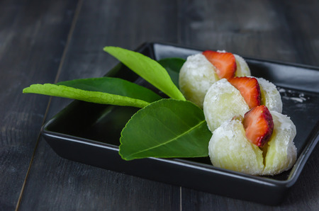 Strawberry Daifuku Mochi Japanese dessert on black dish over wooden backgroundの写真素材