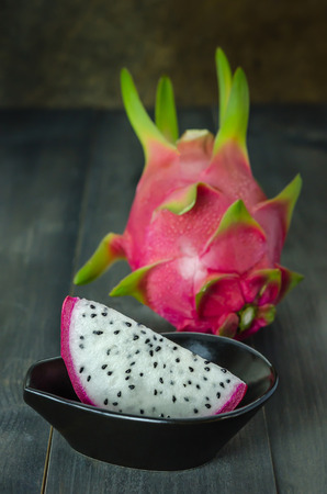 Ripe Dragon fruit  with slice in bowl over wooden background , still lifeの写真素材