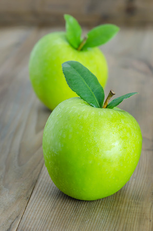 Ripe green apple with leaf  on a wooden backgroundの写真素材