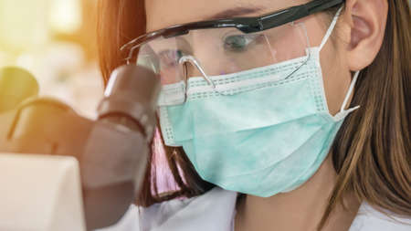 scientist looking through a microscope in a laboratoryの写真素材