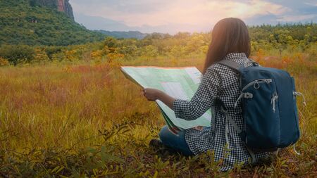 Hipster Asian woman backpacker look map on tripの写真素材