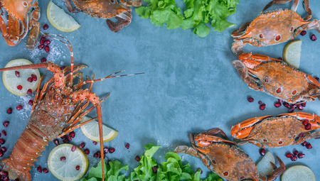 Food frame with crustacean . Lobster, crab, lemon and  pomegranate on backgroundの写真素材