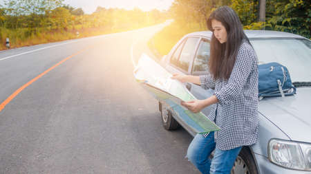 Hipster Asian woman backpacker look map on tripの写真素材
