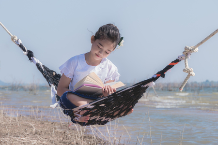 asian little girl reading a book on hammockの写真素材