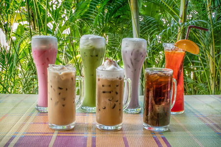 group of iced milk , tea and coffee on table with nature backgroundの写真素材