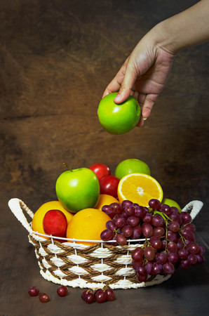 fresh vegetables and fruits in wicker basket over wooden backgroundの写真素材