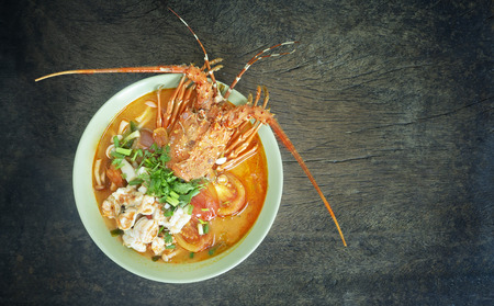 Top view of Tom Yum Goong  , Thai spicy soup in bowl over wooden backgroundの写真素材