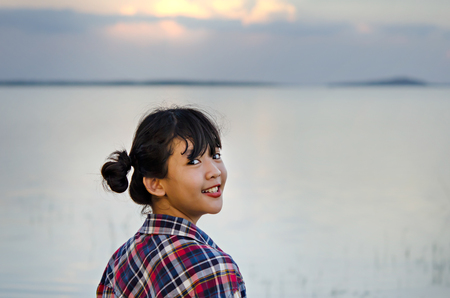 A portrait of a beautiful young asian girl smiling brightly at the cameraの写真素材