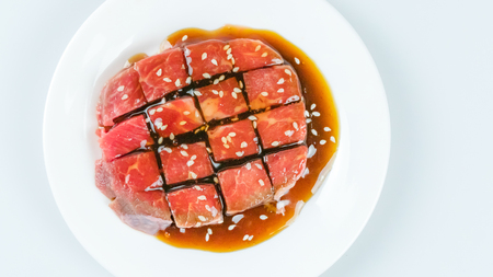 Top view of some raw beef with sauce on a plate over white backgroundの写真素材
