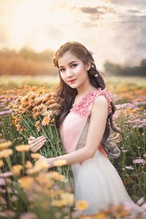 portrait of beautiful asian woman in nature flowers fieldの写真素材
