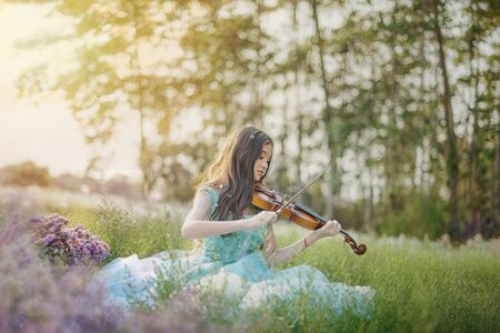 portrait of beautiful asian woman in nature flowers field with violineの写真素材