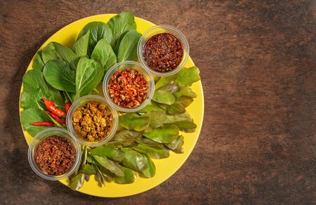 thai style chili paste served with fresh vegetables on yellow plate over wooden backgroundの写真素材