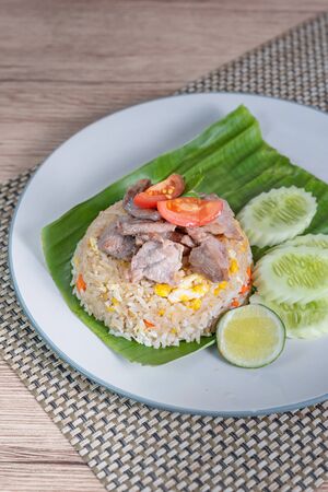 fried rice with pork served with fresh vegetables on dishの写真素材