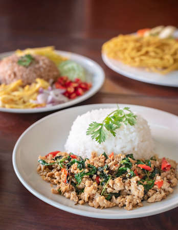 Stir-fried meat with chili and basil served with steamed rice on white dish