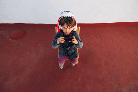 Portrait of five years old child with smartphone and headphones listening to music and playing a video gameの写真素材