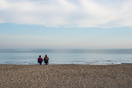 Couple in love sitting on the beach one winter afternoonの写真素材